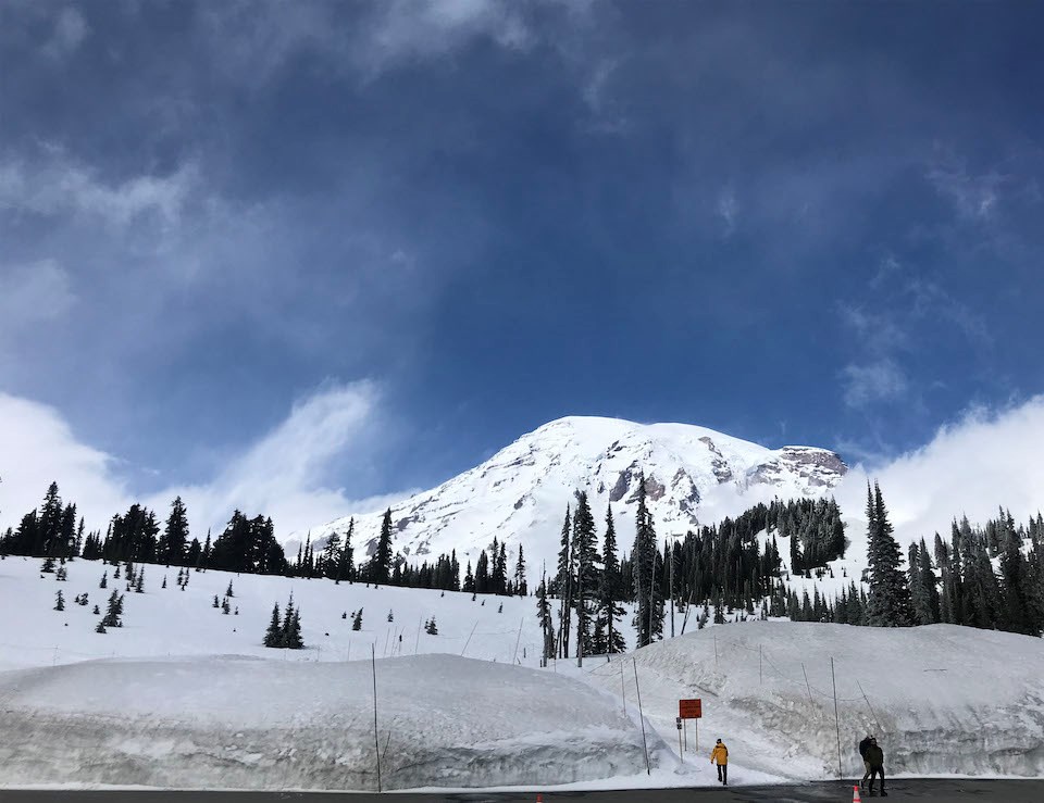 Deep snowbanks surround a parking lot with the view completely obscured by low fog and clouds.